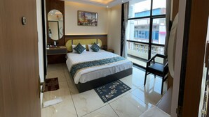 A modern hotel room with a large bed, a desk, a ceiling fan, and a view of the outside. - Hotel Shakuntla Palace 400 mts to Vishnupad Temple (Gaya)