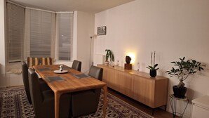 Et moderne spiseområde med et træbord, stole, et tæppe med et mønster og et træskab med pyngegenstande.