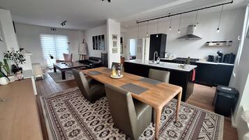 Une cuisine moderne dotée d’un îlot central, un coin repas avec une table et des chaises en bois, et un espace de vie comprenant un canapé et une table basse.