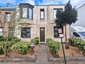 A two-story building with a brick facade, a central entrance, and a mailbox. - B&B De Lelie in Schoten. To get away from the hustle and bustle.   (Schoten)