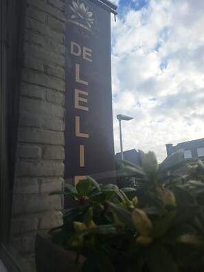 Une façade d’immeuble avec une enseigne verticale sur laquelle on peut lire « DE LELIE ».