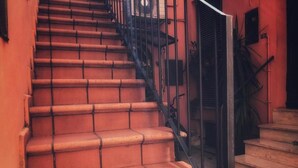 Eine Treppe mit Terrakotta-Stufen und schwarzen Metallgeländern.