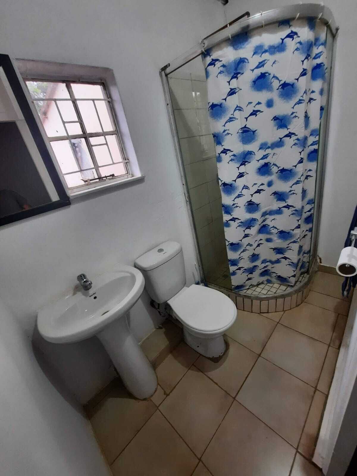 A bathroom with a sink, toilet, and shower area.
