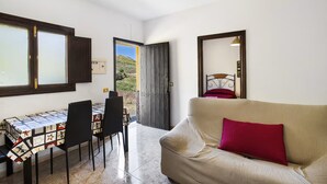 A room with a dining table, chairs, a sofa, and a large mirror. - House The Hut (Galdar)