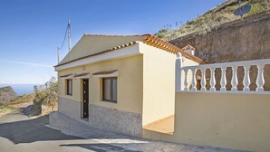 A single-story house with a tiled roof, a white balcony, and a stone wall. - House The Hut (Galdar)