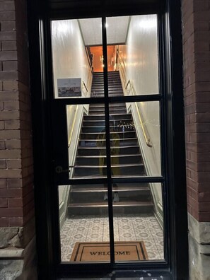 A staircase leading to an upper floor with a 'WELCOME' mat at the bottom. - Upscale Western Inn With Historical Distinction and Modern Comfort (Okemah)