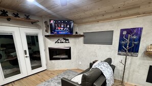 Una sala de estar con sofá, televisión, chimenea y una puerta.