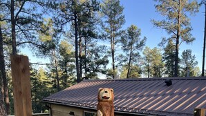 Una cabaña de madera con una escultura de oso sobre un tocón de árbol.