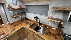Una cocina con encimera de madera, un lavamanos integrado y diversos utensilios de cocina.