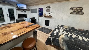 Interior acogedor de una cabaña con una mesa de comedor de madera, un sofá y un televisor montado en la pared.