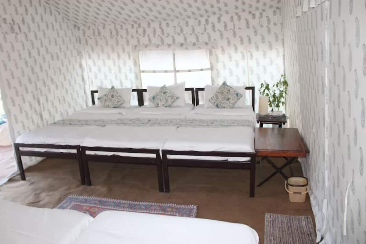 Une chambre à coucher avec un grand lit, une table de chevet en bois, une fenêtre et un papier peint à motifs.