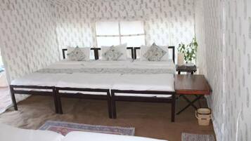 A bedroom with a large bed, a wooden nightstand, a window, and patterned wallpaper.