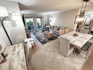 A modern living room with a sofa, coffee table, and dining area. - Sea Winds 78 Oceanfront Beach Community (St. Augustine)