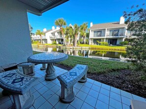 A patio with a mosaic table and benches overlooking a pool and buildings. - Sea Winds 78 Oceanfront Beach Community (St. Augustine)