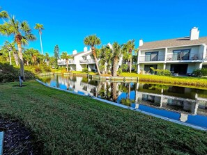 A modern hotel with a reflective water feature in the foreground, surrounded by well-maintained lawns and palm trees. - Sea Winds 78 Oceanfront Beach Community (St. Augustine)