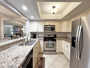A modern kitchen with granite countertops, stainless steel appliances, and white cabinetry.