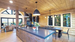 A spacious kitchen with a large island, wooden cabinetry, and pendant lighting.