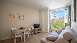 Ein modernes Wohnzimmer mit Essbereich, einem Flachbildfernseher und einem großen Fenster mit Blick auf die Stadt.