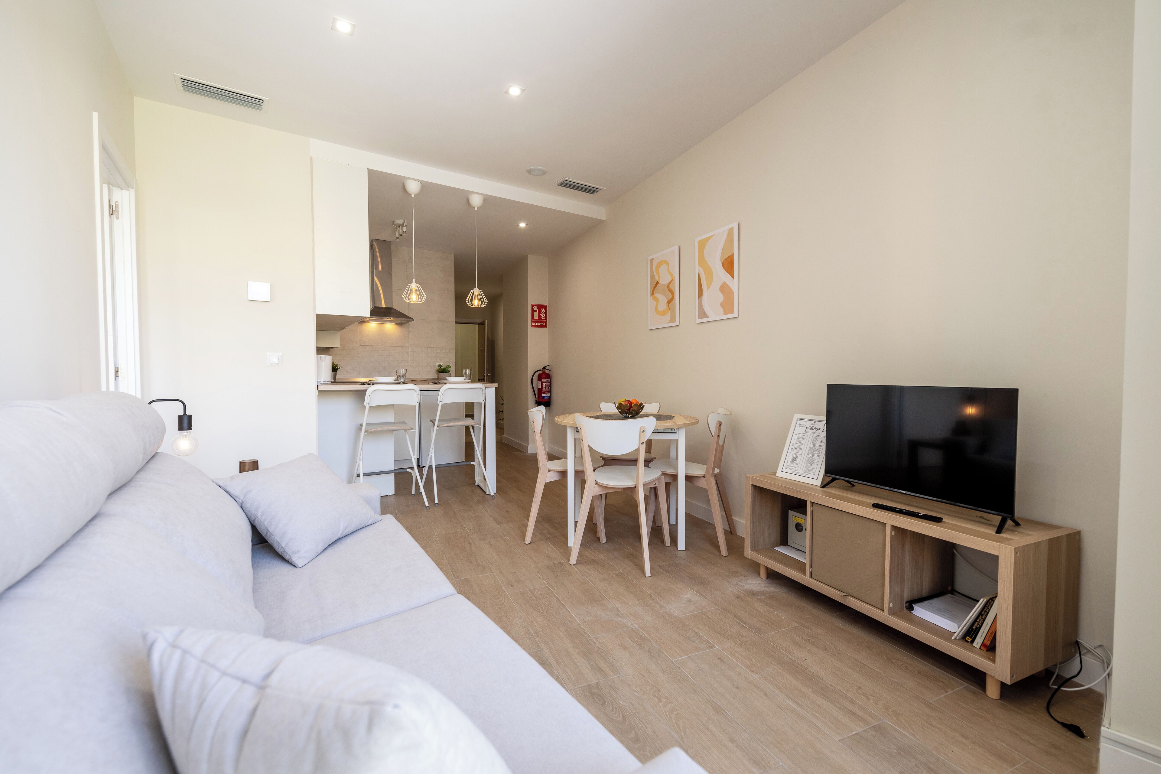 Una sala moderna con sofá, televisor y comedor.