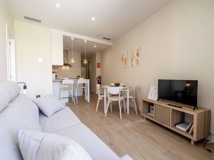 Una sala moderna con sofá, televisor y comedor.