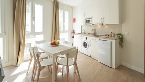 Eine moderne Küche mit weißen Geräten, einem Esstisch mit Stühlen und einer Waschmaschine.
