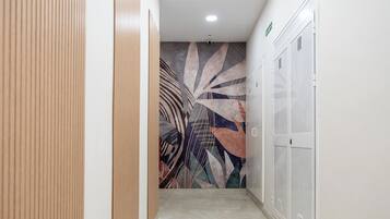 Un pasillo con taquillas, un papel tapiz decorativo y una lámpara en el techo.