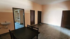 Guest room with a table and chairs, sink, and door to a hallway with a staircase.