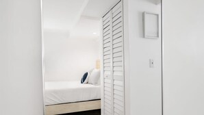 Un dormitorio con cama, armario y espejo.