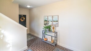 A hallway with a gray console table, a wreath on the door, and three framed pictures on the wall.