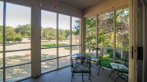 A sunroom with large windows, a glass table, and two chairs.