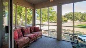 A sunroom with a wicker sofa, large windows, and a ceiling fan.