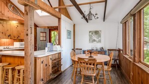 A rustic wooden interior with a dining area, wooden stools, and a kitchen with a microwave.