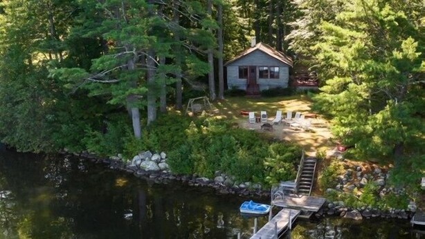 A cabin surrounded by dense forest, a dock, and a small boat.