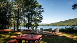 A lakeside picnic area with a red table and chairs, surrounded by trees and overlooking a lake.