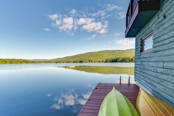 Una cabaña de madera a orillas de un lago tranquilo con cielo despejado.