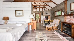 A rustic cabin with a loft bedroom, a dining area, and a fireplace. - Charming boathouse for two with deck overlooking Lake Kanasatka (Moultonborough)