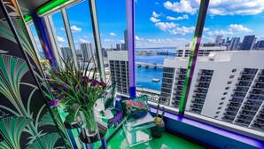A modern room with large windows, a view of a city skyline, and a balcony with potted plants. - Disco Cloud Condo in Miami (Miami)
