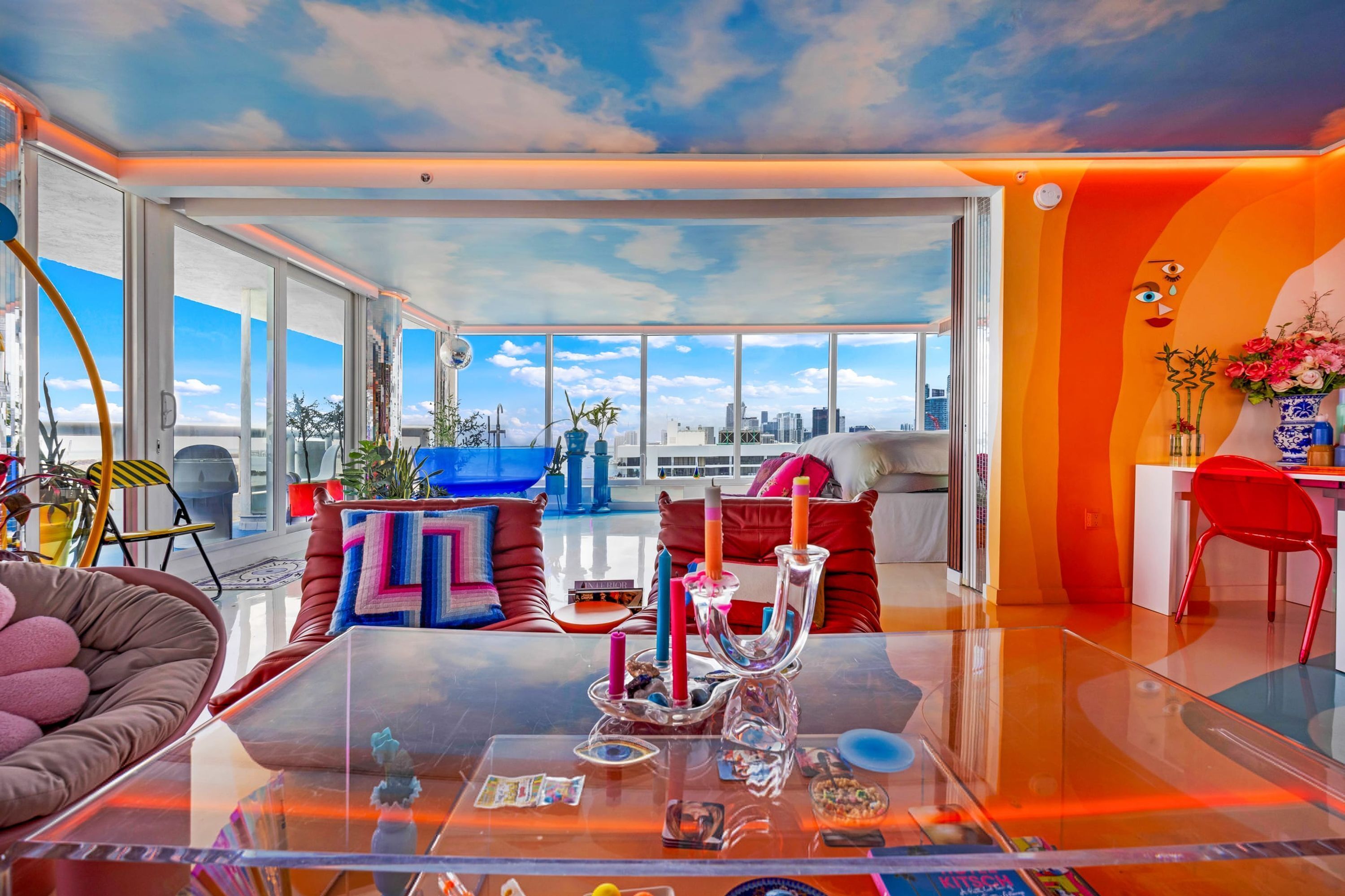 Una sala de estar moderna con ventanas amplias, una mesa de centro de vidrio y vistas a la ciudad.