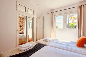 Habitación de hotel con dos camas, un armario y un ventanal con vistas a árboles.