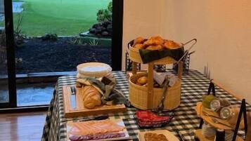 Una mesa de buffet con diferentes opciones de comida y vista a un campo de golf a través de un ventanal grande.