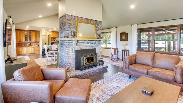 A spacious living room with a brick fireplace, leather sofas, and a wooden coffee table. - Kansas Gem w/ Fire Pit & Views: 10 Mi to Dtwn! (Manhattan)