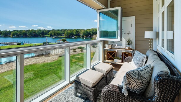 A balcony with wicker furniture, a TV, and a view of a lake. - Beach + Pool Access: Smith Mountain Lake Getaway! (Huddleston)