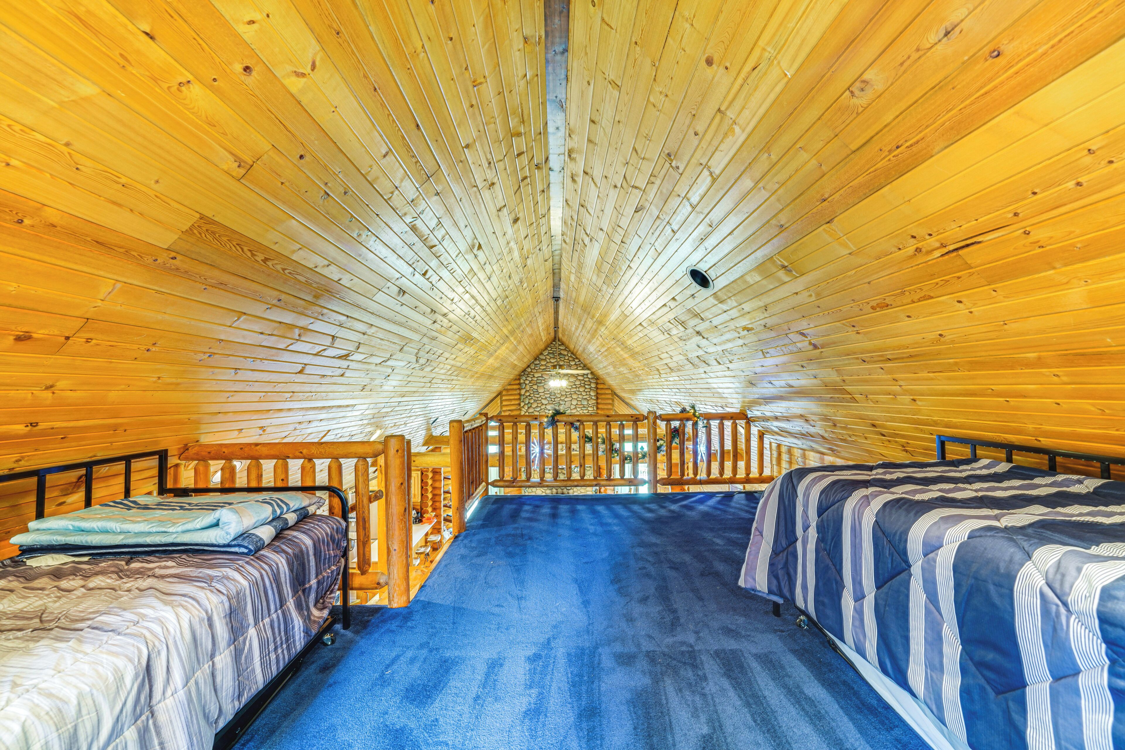 A cabin with a wooden interior, a loft bed, and a blue carpet.