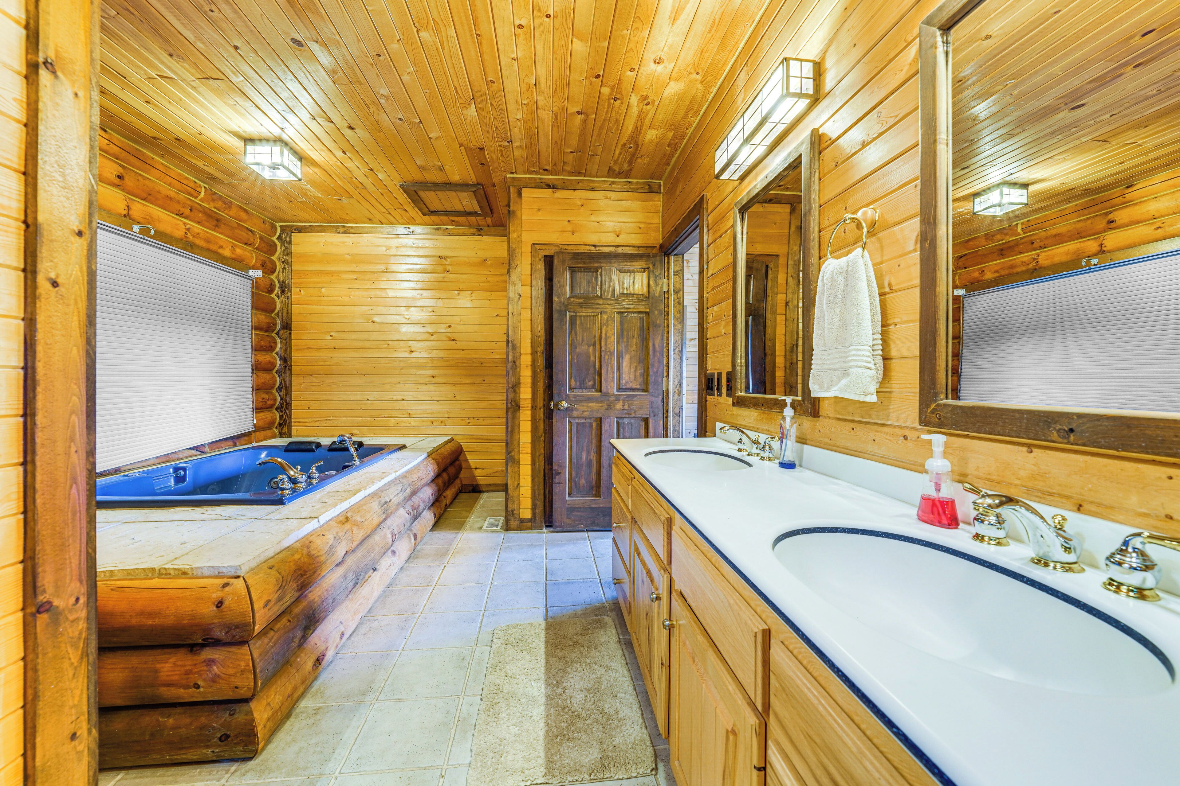 A wooden cabin bathroom with a bathtub, a sink, and a mirror.