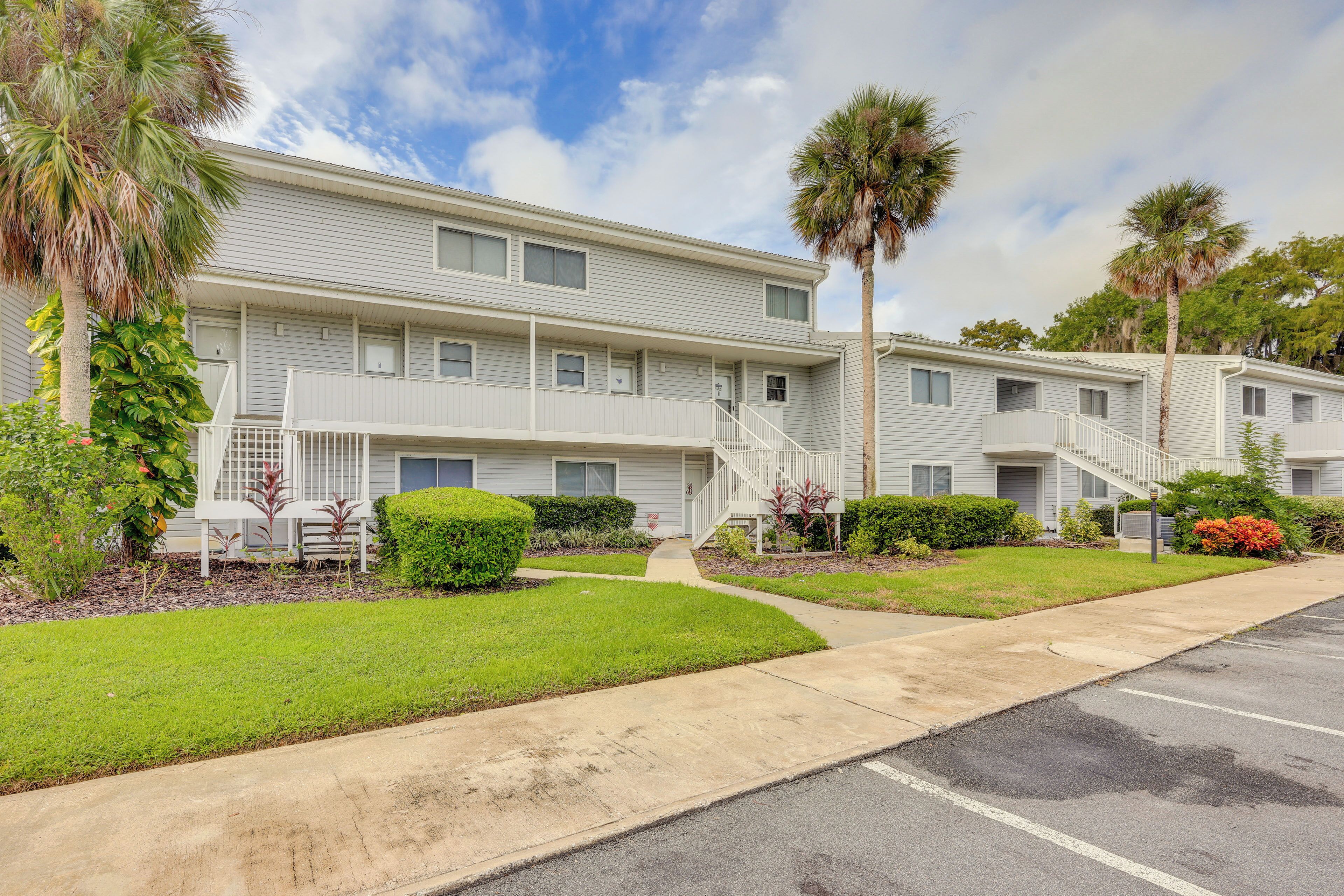 A multi-story motel with a central walkway, palm trees, and a parking lot.
