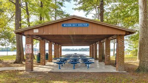 A pavilion named Wilson Bay Shelter with picnic tables and a 'No Sleeping on the Tables' sign. - 3 Mi to Camp Lejeune: Home w/ Fire Pit & Grill! (Jacksonville)