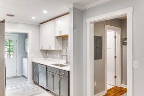 A modern kitchen with white cabinets, a stainless steel sink, and a wooden countertop.