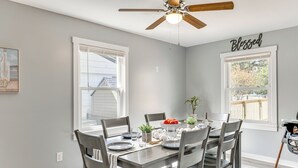 A dining area with a wooden table, grey chairs, and a ceiling fan. - 3 Mi to Camp Lejeune: Home w/ Fire Pit & Grill! (Jacksonville)