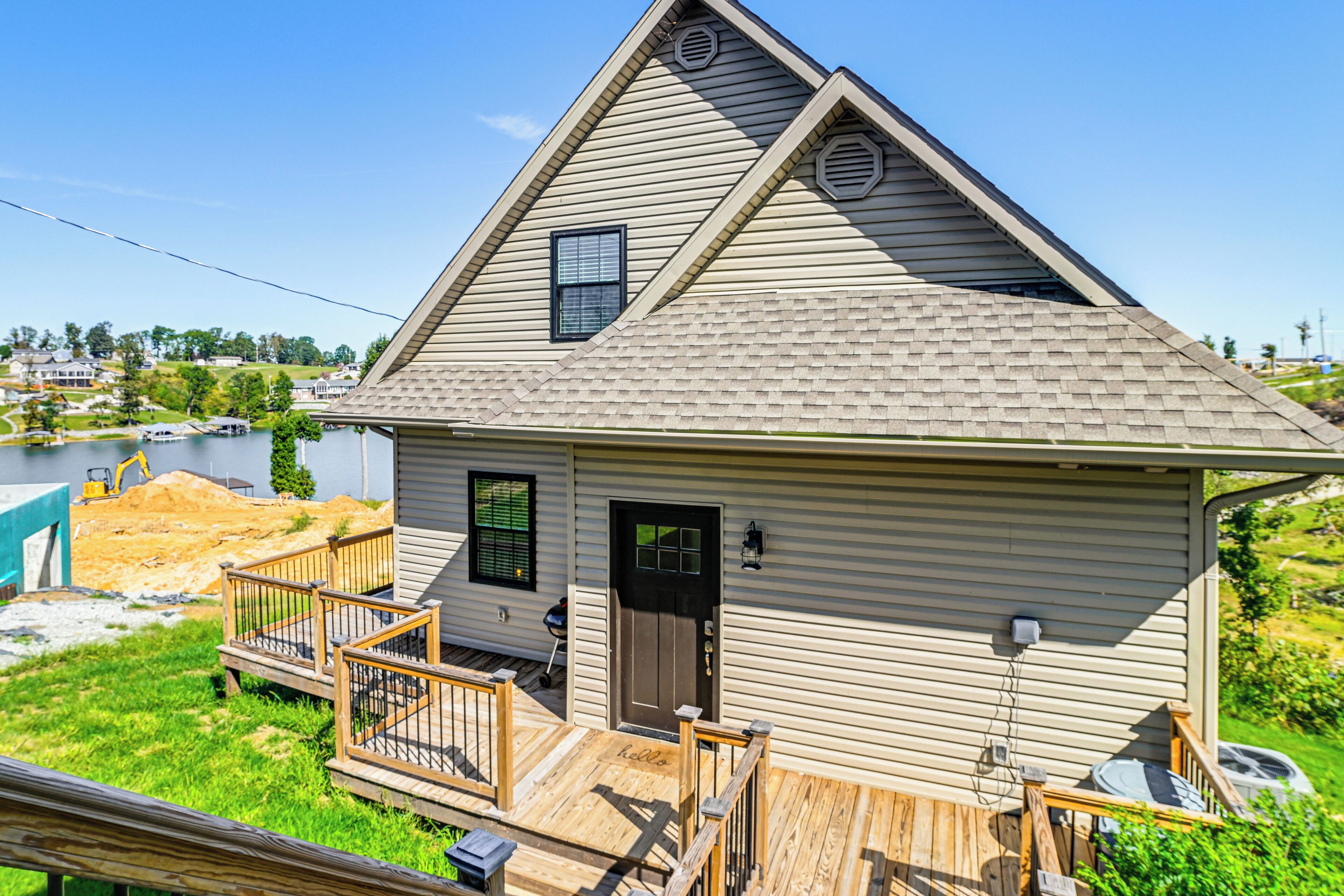 A single-story house with a sloped roof, a front porch with a railing, and a small deck.