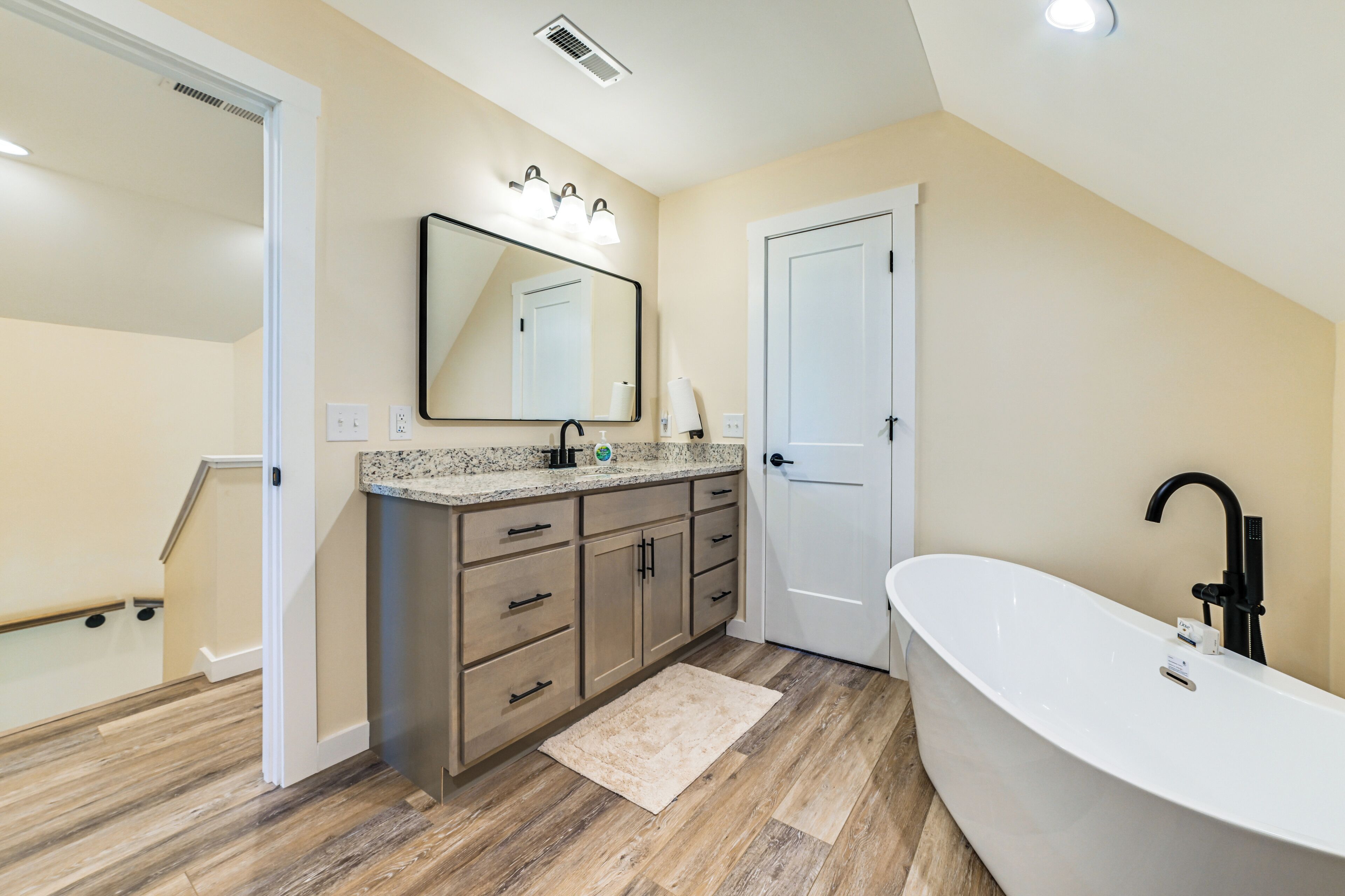 Une salle de bain moderne avec une baignoire sur pieds, des meubles en bois et un grand miroir.